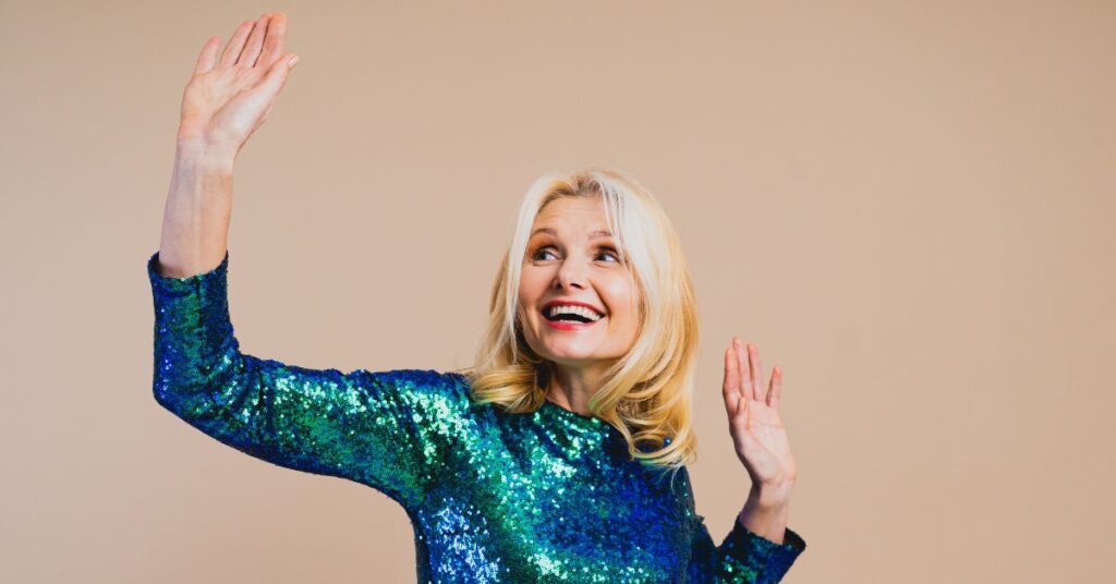 person grinning, arms up, wearing sequins, celebrating