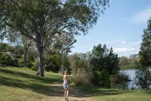 Woman In White Tank Top And Blue Shorts Standing On Green Grass